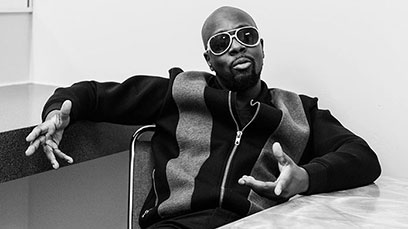 Wyclef lamping in what appears to be an office in an elementary school